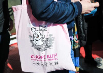 Ein Mann trägt die rosa Festivaltasche